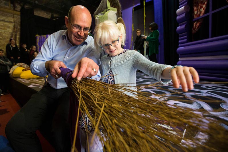 Tim Bray and a young girl touch a broomstick during a touch tour of Bad Jelly the Witch