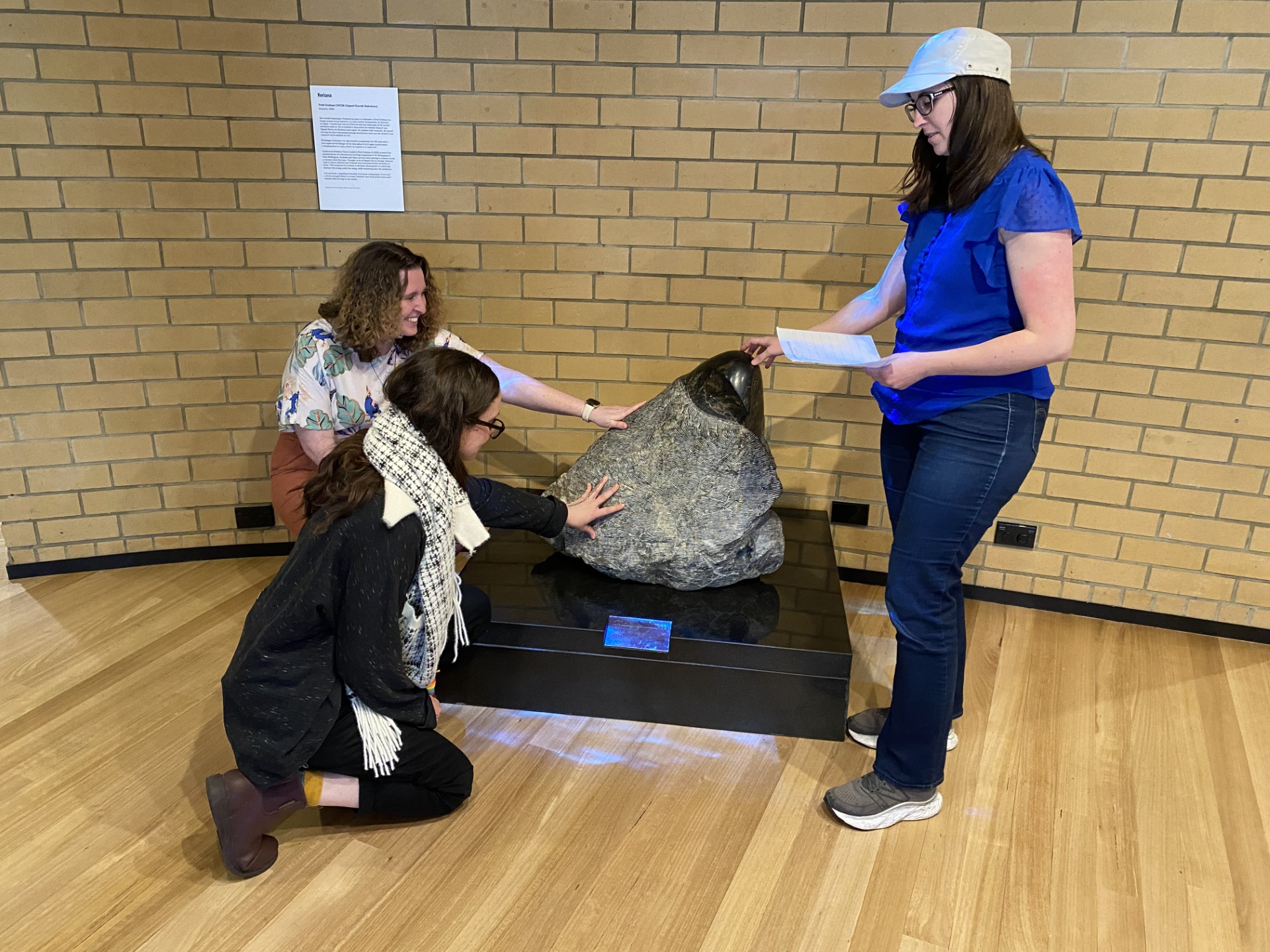 Katie Querin joins fieldtrip participants in running their hands over a stone taonga at Waikato Museum which features both a rough and smooth surface that visitors are encouraged to touch.