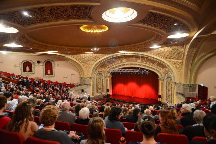 Inside the Regent Theatre auditorium, where people are seated and looking down on the stage
