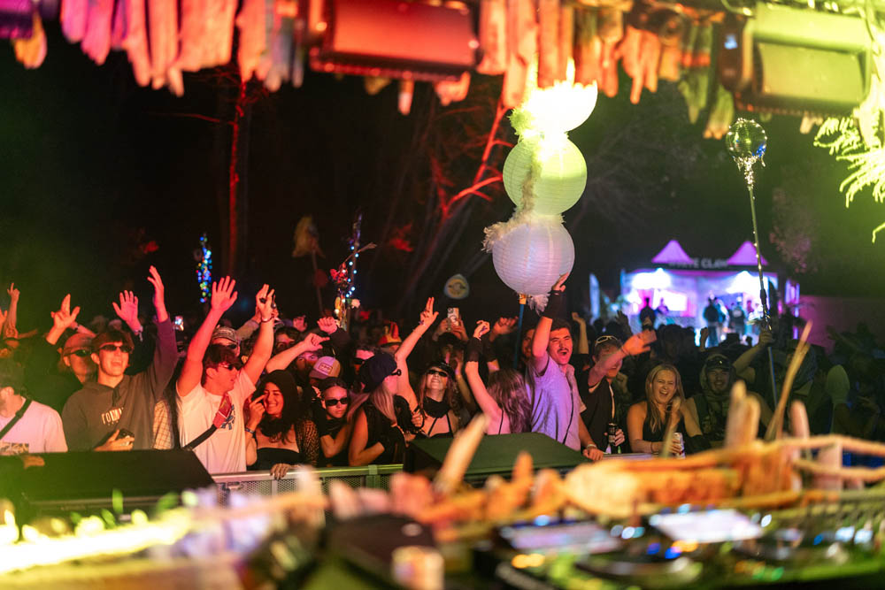 A crowd of festival-goers from the DJ booth dancing at night, bathed in yellow and orange light with their hands high Photo: Lucas Perelini