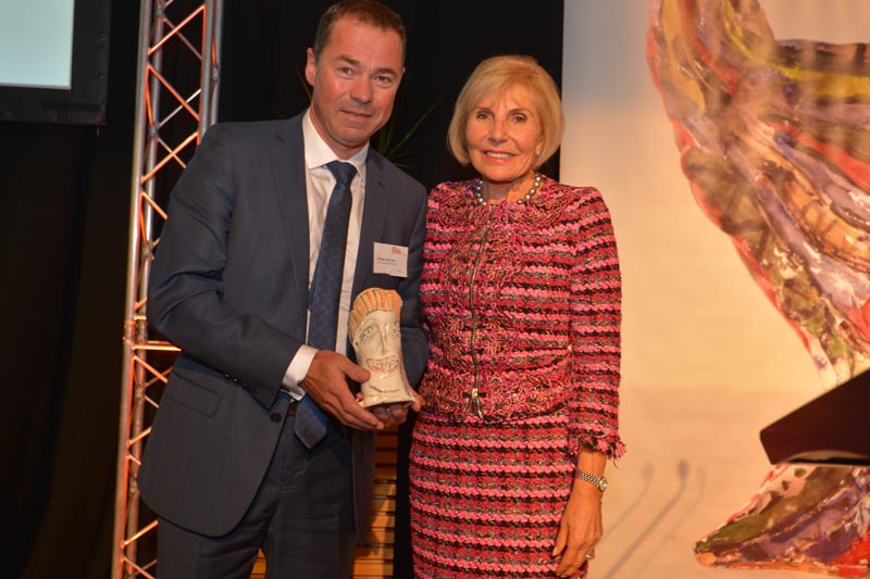Oliver and Dame Rosie Horton pose together for a photo with Olivier's award held in his hands.